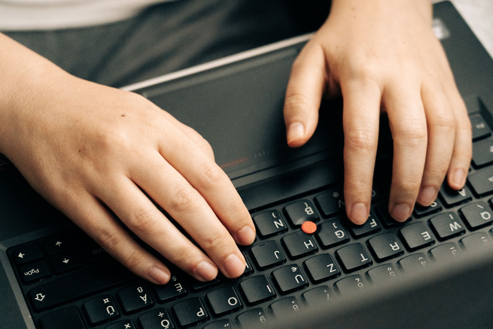 Close-up of two hands typing on a black laptop keyboard